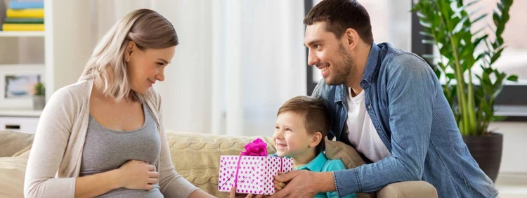 Pregnancy gift for wife: A man and a child hand over a present to a pregnant woman