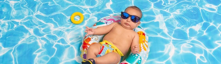 6 month old baby swimming in water relaxing on a lilo